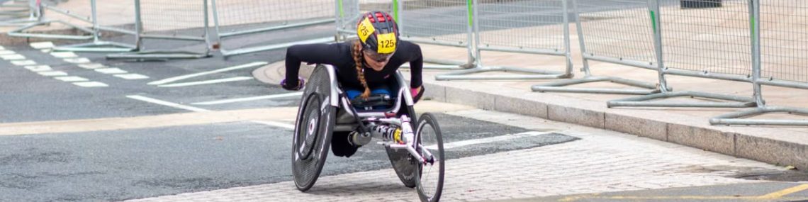 A dedicated athlete competes in a marathon using a racing wheelchair on city streets.